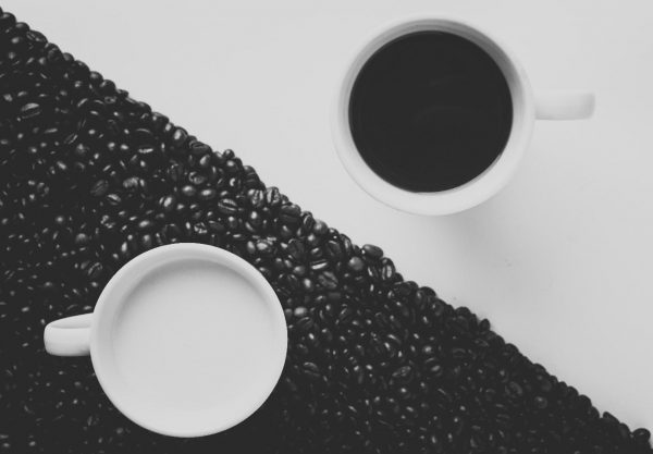 A black mug on a white background, next to a white mug on a black background