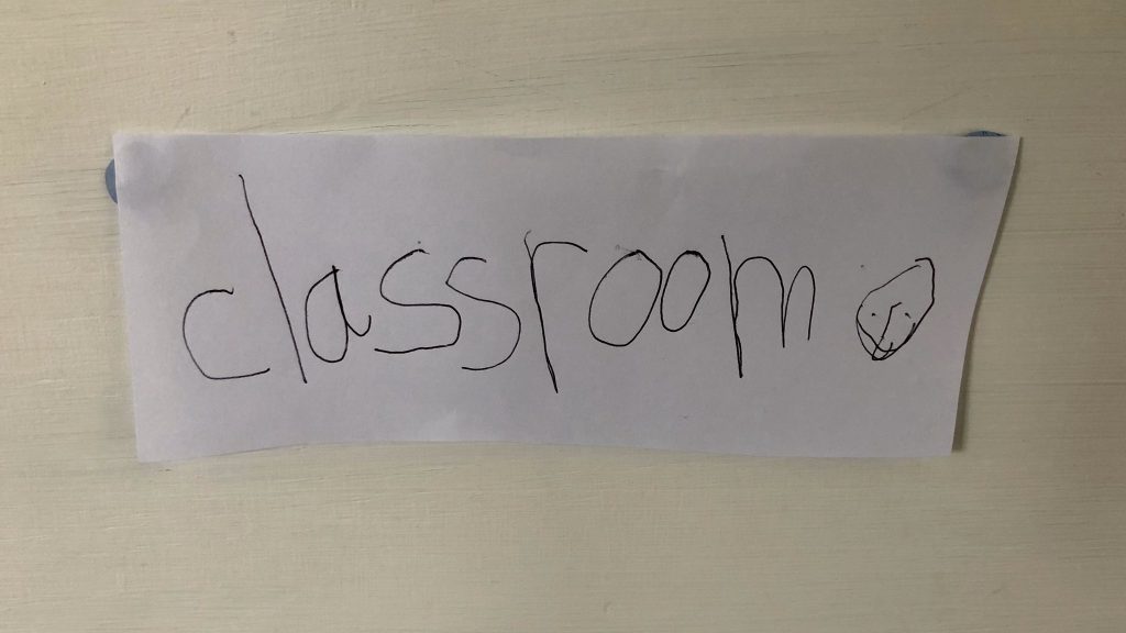 Hand written sign, child's writing, says "classroom".