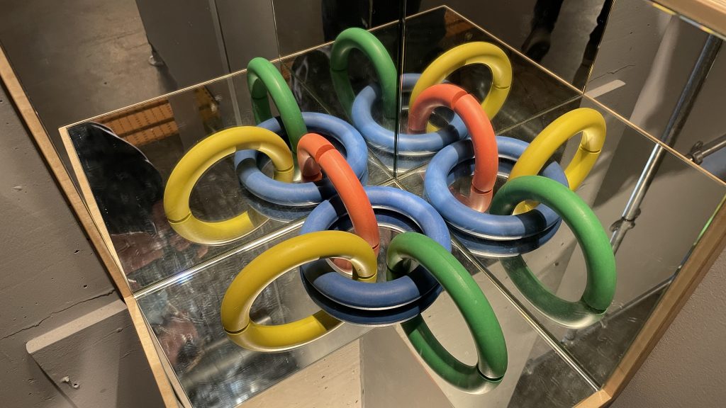 Four coloured rings or part rings reflected in three orthogonal mirrors.
