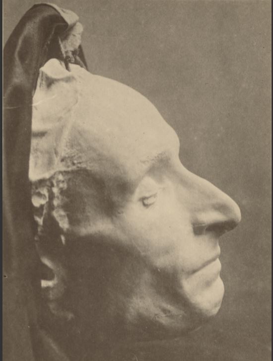 Old photograph of a death mask, which looks like a plaster case of a sleeping man's face, seen from the side