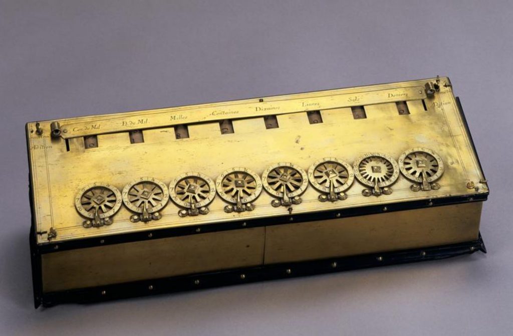 A photo of a gold metal box, with a set of dials on the front and numbers showing through holes across the top.