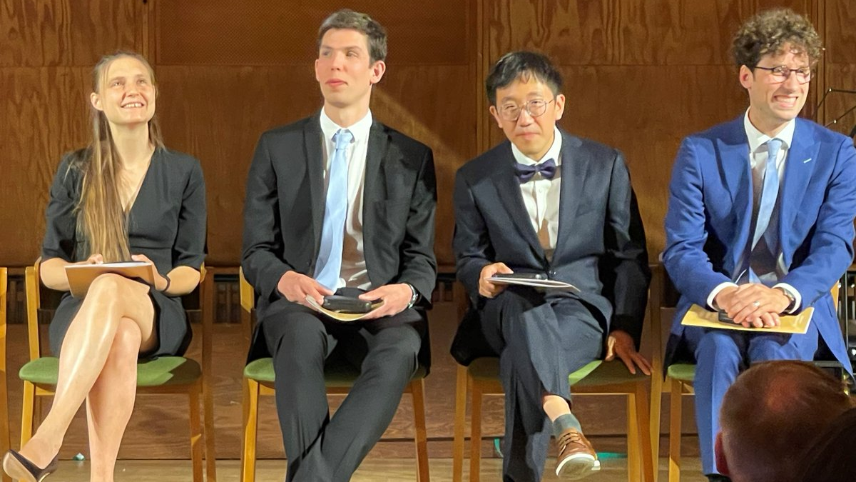 Photograph of the four 2022 Fields Medalists sitting in a row at the award ceremony