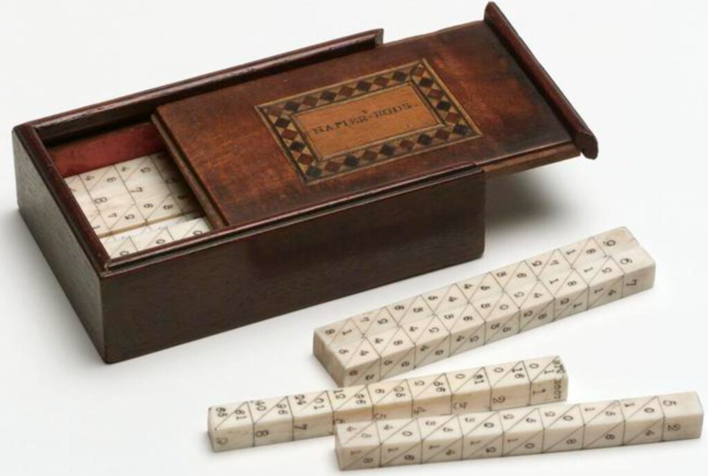 A set of 18th century ivory Napier's bones, 4 on a table and the rest inside a wooden box. The box lid slides out and has a patterned inlay.