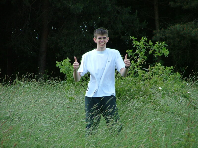 Christian in the middle of a field, with two thumbs up