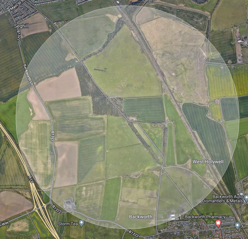 Screenshot of a map in satellite view, with a circle centred on a country road surrounded by fields.