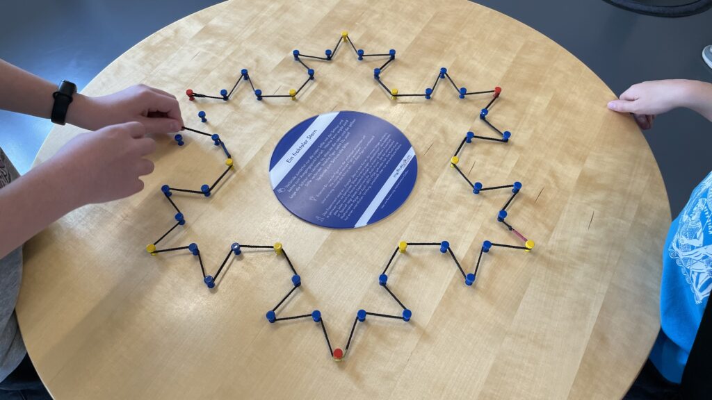 Pins and string forming a third-stage Koch snowflake pattern.