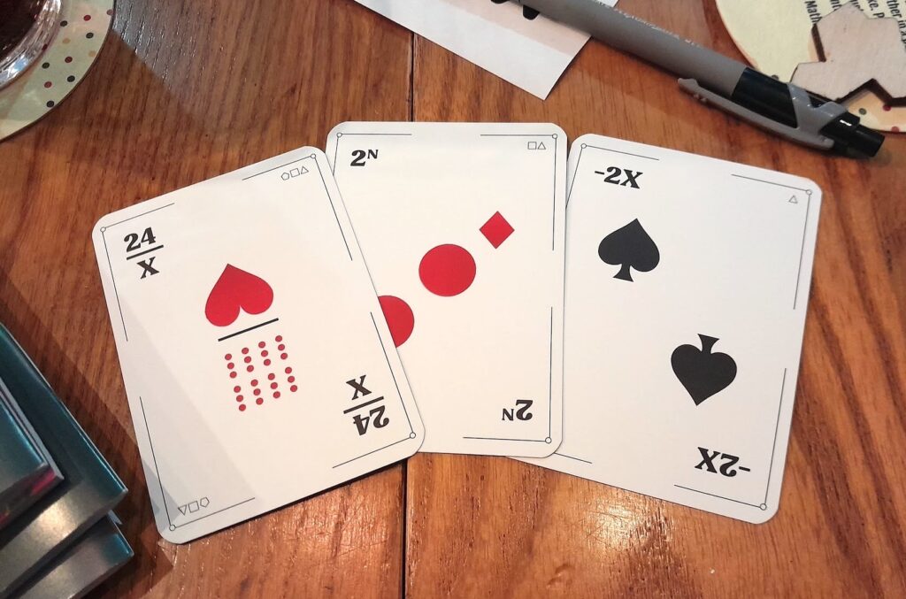 The cards 24/X, 2^N and -2X arranged on the table in a pub