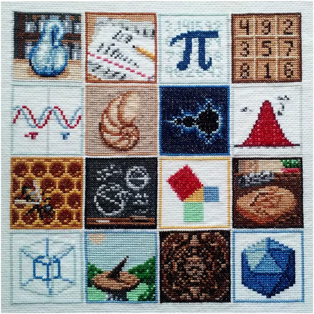 Photo of mathematical cross-stitch made up of 16 individual tiles each with a different mathematical design, including Klein bottle, pi, sine curves, Mandelbrot, a normal curve, Pythagoras' theorem, a hypercube and an icosahedron