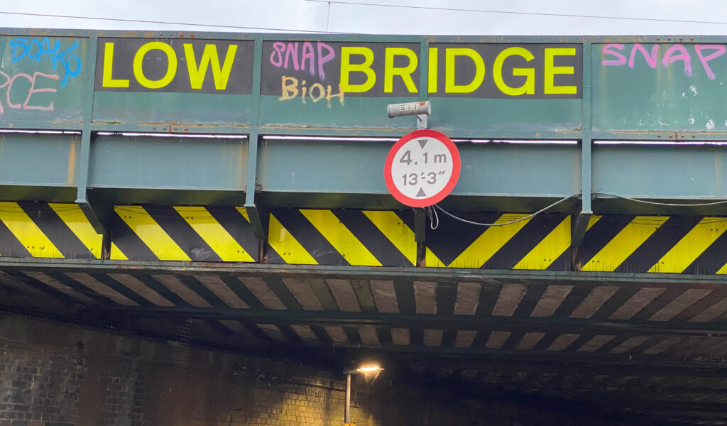 Low bridge sign attached to a bridge reading 4.1m and 13'-3''.