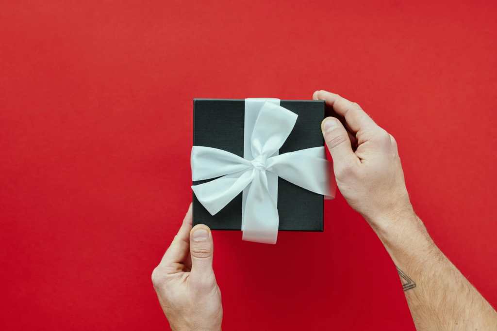 Black Gift Box With White Ribbon, held in someone's hands