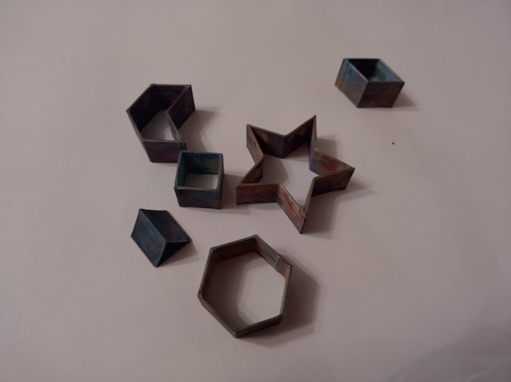 The stampers: a star, regular hexagon, chevron, rhombus, square and triangle. They are all the same height and all the sides are the same length.