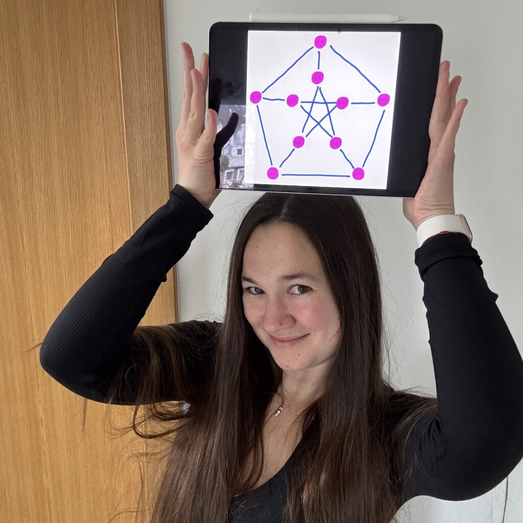 Photo of Kala, who is a young white woman with long dark hair, holding a K5 graph above her head and smiling