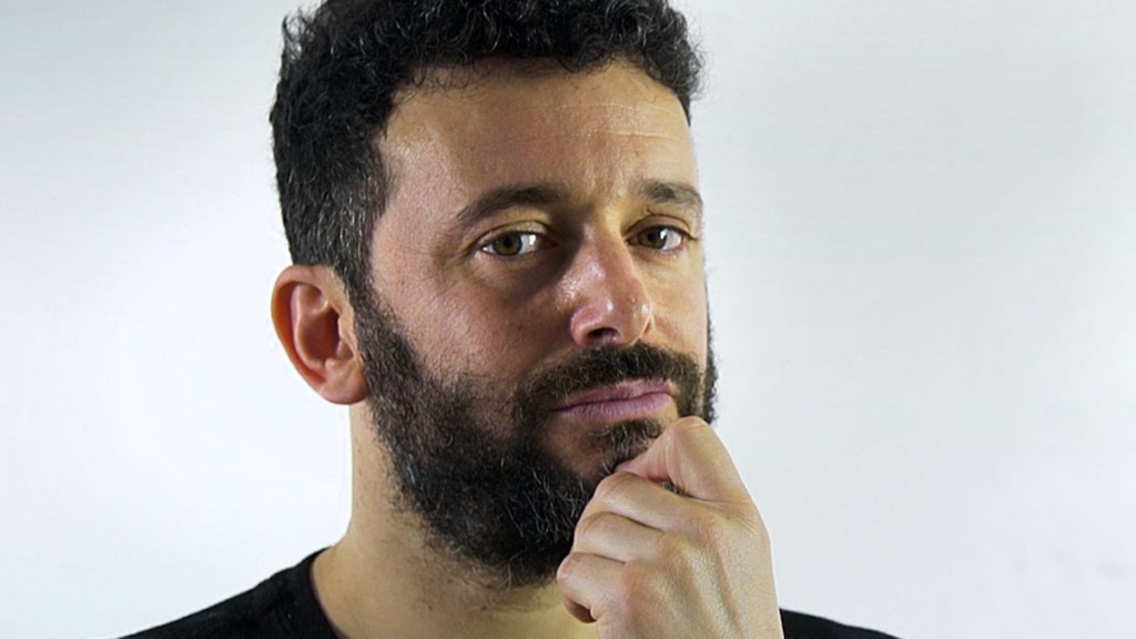 Photo of Alex Bellos, a white man with short dark hair and beard, looking pensive